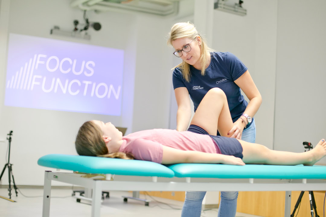 Physiotherapeutin führt Beinmobilisation bei Schülerin durch zur Vorbereitung auf Return-to-Schulsport nach Verletzung