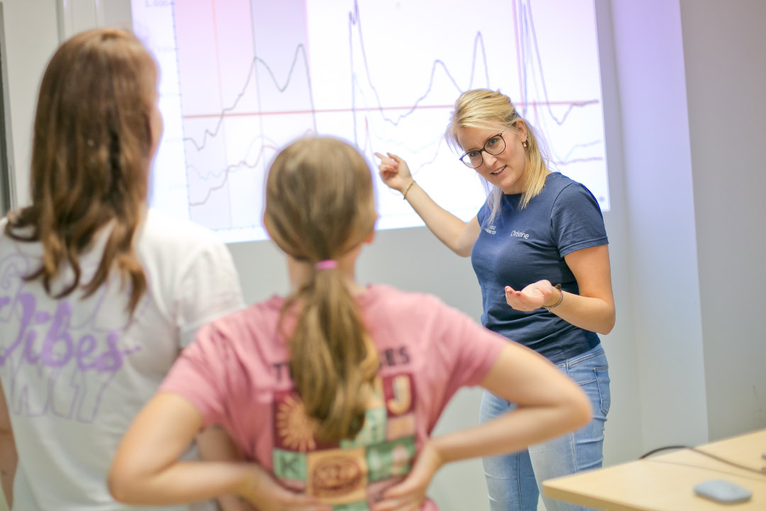 Sporttherapeutin erklärt zwei Schülerinnen Auswertung von Bewegungs- und Kraftdaten im Rahmen des Return-to-Schulsport-Programms